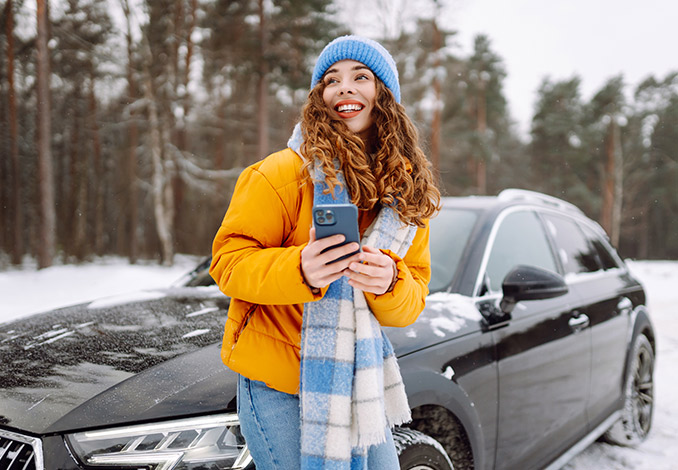 Woman in a bright yellow jacket leaning on a car