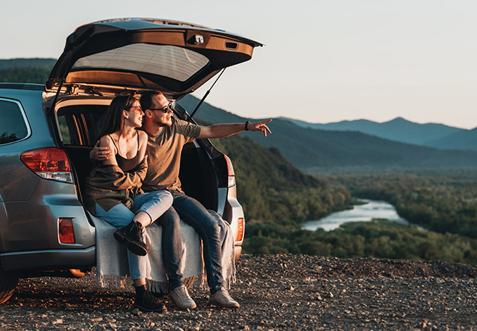 couple watching the sunset from the trunk of their car
