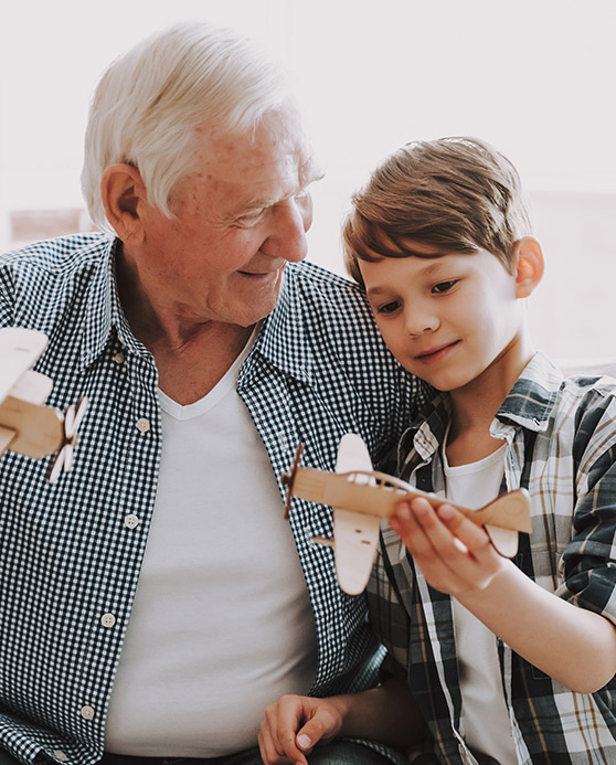 Grandfather and grandson playing with toy airplanes together.