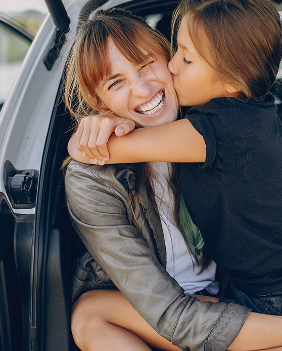 Mom and daughter laughing while sitting in the trunk of a car