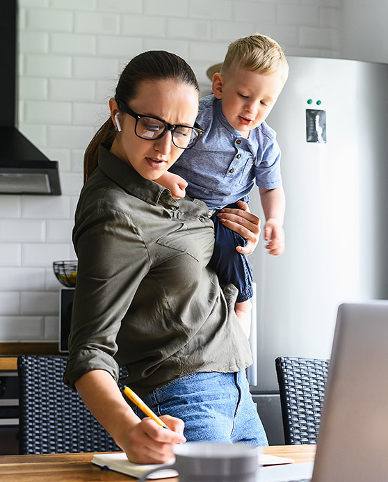Mom carrying toddler on hip while writing something down