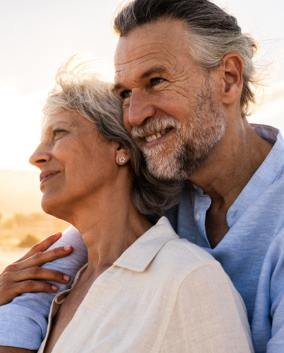 Older couple embracing while watching the sunset on the beach