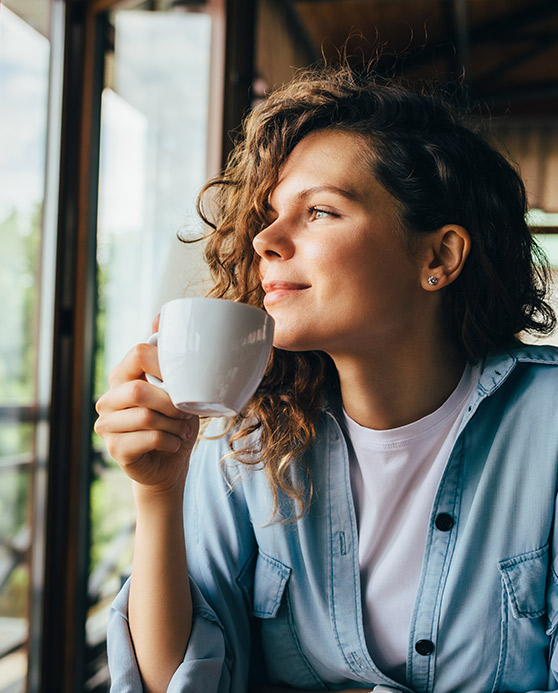 Woman sipping coffee while looking out a window
