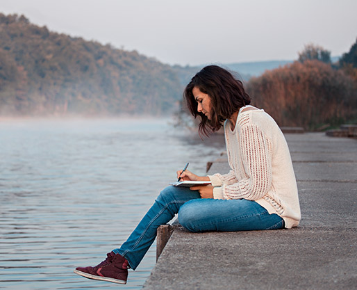 Woman writing a letter by a lake